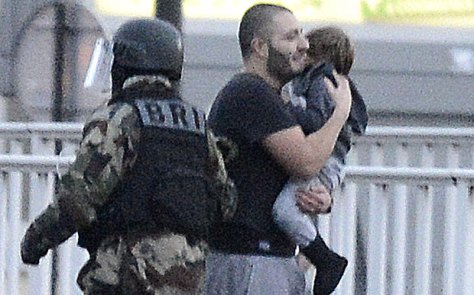 SAVED: A hostage holding a child shows his relief after paramilitary police stormed the kosher deli in eastern Paris